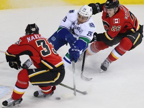 Calgary Flames Jakub Nakladal and Tyler Wotherspoon battle against Emerson Etem of the Vancouver Canucks during NHL hockey in Calgary, Alta., on Friday, February 19, 2016. Al Charest/Postmedia