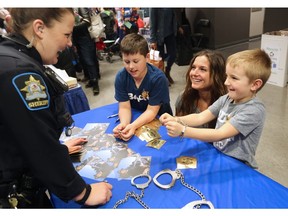 Gabe Stan, 6 tries out some handcuffs with brother, Josh, 9 and mom Elena at the Alberta Sheriffs display at the Calgary Courts Centre on Law Day 2016 - Saturday, April 16, 2016.