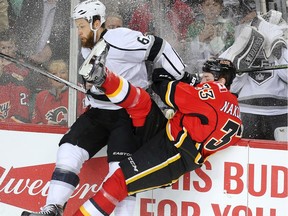 Jake Muzzin of the Los Angeles Kingsslams into the boards with Jakub Nakladal of Calgary Flames at the Saddledome during the first period Tuesday April 5, 2016.