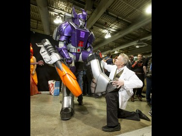 Dr. Brian Abelson has a look at the giant foot of Transformer Anthony Quinton during the Calgary Comic and Entertainment Expo at Stampede Park in Calgary, Alta., on Saturday, April 30, 2016. Lyle Aspinall/Postmedia Network