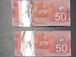 Counterfeit $50 bills seized by RCMP in Cochrane are pictured. Police say the bills were made from paper, not polymer, and the holographic portions of the bills were cut from $5 and $10 and taped onto the counterfeits.