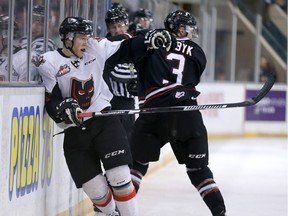 Hitmen Beck Malenstyn (L) is hit by Rebels Colton Boybk along the boards during Western Hockey League playoff action between the Red Deer Rebels and the Calgary Hitmen at the Stampede Corral in Calgary on April 1, 2016.