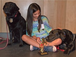 Madison Congdon, 9, cuddles police and fire service dogs after receiving her 9-1-1 Heroes Award in Calgary on April 8, 2016. The 9-1-1 Heroes Awards honour children who have helped someone in need by calling the emergency number.