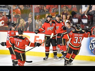 The Calgary Flames forward Joe Colborne, centre right, and defenseman Deryk Engelland, centre left, celebrate with teammates after scoring against the Vancouver Canucks during hockey action at the Scotiabank Saddledome in Calgary, AB., on Thursday, April 7, 2016.  The Flames won the NHL regular season game 7-3. (Photo by Andy Maxwell Mawji/ Postmedia)