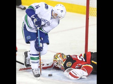 Calgary Flames goalie Joni Ortio eyes a loose puck in his crease in front of Vancouver Canucks forward Alexandre Burrows during the first period at the Saddledome Thursday night April 7, 2016.  (Ted Rhodes/Postmedia)