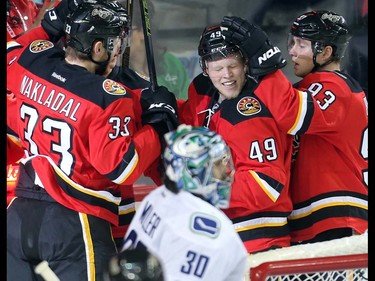 The Calgary Flames, including Hunter Shinkaruk, centre, Jakub Nakladal, left, and Sam Bennett, right,  celebrate in front of Vancouver Canucks goalie Ryan Miller after their first goal of the first period at the Saddledome Thursday night April 7, 2016.  (Ted Rhodes/Postmedia)