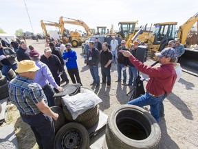 Tires and tree covers are auctioned off near a lineup of excavators during an industrial sale at Graham Auctions in Calgary on Wednesday. Graham Auctions said it was one of the largest sales they'd ever held.
