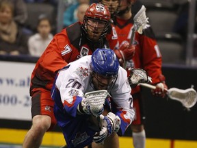 Toronto Rock Bradley Kri (20) is checked  by Calgary Roughnecks Tyler Burton (7)  in the fourth quarter during the National Lacrosse League action at the ACC in Toronto, Ont. on March 11, 2016.