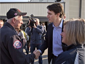 Prime Minister Justin Trudeau shakes hands with Fort McMurray Fire Chief Darby Allen before visiting the flame-stricken city on Friday.