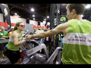 Arielle Fitzgerald gets some love from Dave Proctor as she finishes her world record attempt and he carries on with his during the Calgary Marathon Expo at the Big Four Building in Calgary, Alta., on Saturday, May 28, 2016. Seven world records for treadmill running were broken, including Dave Proctor's 24-hour run, all in support of MitoCanada. Lyle Aspinall/Postmedia Network