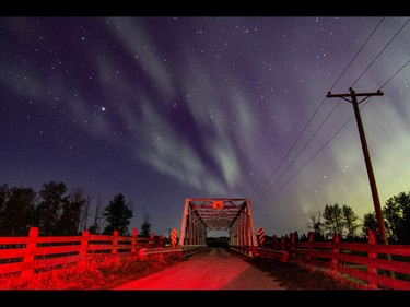 Aurora borealis lights up the night as brake lights add a red glow to a bridge over Jumpingpound Creek west of Calgary, Ab., on Sunday May 8, 2016. Mike Drew/Postmedia