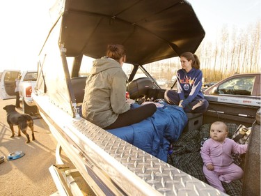 A family takes refuge in the back of their boat after evacuation at a rest stop near Fort McMurray on Wednesday, May 4, 2016.