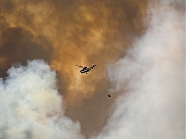 A helicopter battles a wildfire in Fort McMurray, Alta., on Wednesday May 4, 2016. The wildfire has already torched 1,600 structures in the evacuated oil hub of Fort McMurray and is poised to renew its attack in another day of scorching heat and strong winds.THE CANADIAN PRESS/Jason Franson ORG XMIT: EDM121