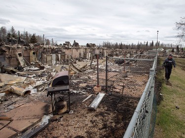 A police officer walks past an apartment complex destroyed in the wildfire in the Abasands neighbourhood in Fort McMurray, Alta., on Monday, May 9, 2016.