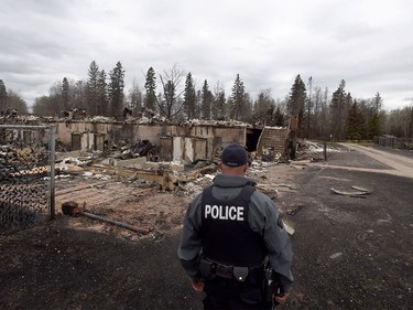 A police officer looks over a fire-damaged building in the Abasands neighbourhood in Fort McMurray, Alta., Monday, May 9, 2016.