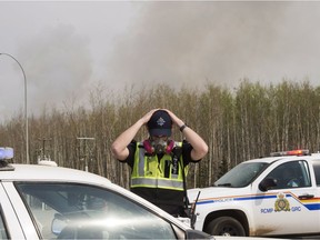 An RCMP officer puts on his gas mask before heading on the highway to Fort McMurray as wildfires are still burning out of control Saturday, May 7, 2016.
