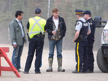 Alberta Wildrose Leader Brian Jean, centre, talks with police near a wildfire in Fort McMurray, Alta., on Thursday, May 5, 2016. Jean's house was burned down in the fire. An ever-changing, volatile situation is fraying the nerves of residents and officials alike as a massive wildfire continues to bear down on the Fort McMurray area of northern Alberta.