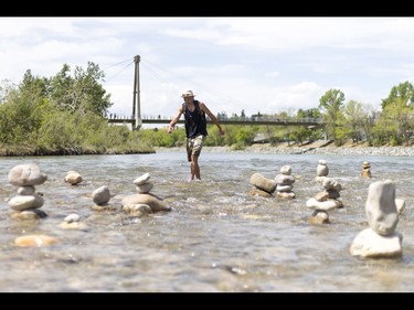 A young man who would only be identified as 'Show Biz' tediously builds cairns, or 'living rocks', in the Bow River at Prince's Island Park in downtown Calgary, Alta., on Wednesday, May 18, 2016. Show Biz says his cairns serve a variety of artistic, therapeutic and calming purposes, his favourite of which is creating a sense of welcomeness and community in an area too often hit with petty crime. Lyle Aspinall/Postmedia Network