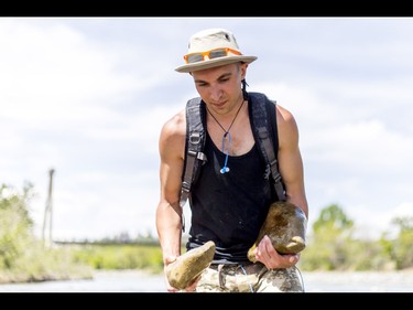 A young man who would only be identified as 'Show Biz' tediously builds cairns, or 'living rocks', in the Bow River at Prince's Island Park in downtown Calgary, Alta., on Wednesday, May 18, 2016. Show Biz says his cairns serve a variety of artistic, therapeutic and calming purposes, his favourite of which is creating a sense of welcomeness and community in an area too often hit with petty crime. Lyle Aspinall/Postmedia Network