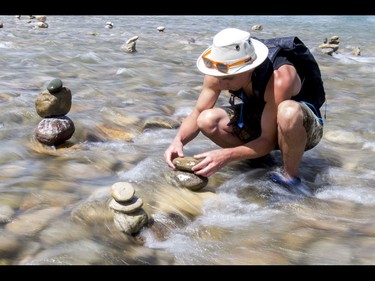 A young man who would only be identified as 'Show Biz' tediously builds cairns, or 'living rocks', in the Bow River at Prince's Island Park in downtown Calgary, Alta., on Wednesday, May 18, 2016. Show Biz says his cairns serve a variety of artistic, therapeutic and calming purposes, his favourite of which is creating a sense of welcomeness and community in an area too often hit with petty crime. Lyle Aspinall/Postmedia Network