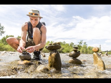 A young man who would only be identified as 'Show Biz' tediously builds cairns, or 'living rocks', in the Bow River at Prince's Island Park in downtown Calgary, Alta., on Wednesday, May 18, 2016. Show Biz says his cairns serve a variety of artistic, therapeutic and calming purposes, his favourite of which is creating a sense of welcomeness and community in an area too often hit with petty crime. Lyle Aspinall/Postmedia Network