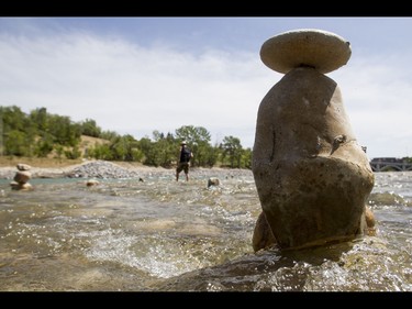 A young man who would only be identified as 'Show Biz' tediously builds cairns, or 'living rocks', in the Bow River at Prince's Island Park in downtown Calgary, Alta., on Wednesday, May 18, 2016. Show Biz says his cairns serve a variety of artistic, therapeutic and calming purposes, his favourite of which is creating a sense of welcomeness and community in an area too often hit with petty crime. Lyle Aspinall/Postmedia Network