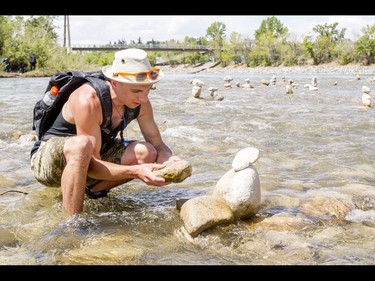 A young man who would only be identified as 'Show Biz' tediously builds cairns, or 'living rocks', in the Bow River at Prince's Island Park in downtown Calgary, Alta., on Wednesday, May 18, 2016. Show Biz says his cairns serve a variety of artistic, therapeutic and calming purposes, his favourite of which is creating a sense of welcomeness and community in an area too often hit with petty crime. Lyle Aspinall/Postmedia Network