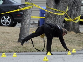 A police officer sets out  evidence markers at the scene on Butler Crescent NW in Calgary Tuesday April 15, 2014 near where five people  were stabbed to death overnight.