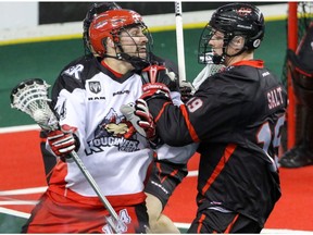 Calgary Roughnecks Wesley Berg shoves his way past Vancouver Stealth Justin Salt in NLL action at the Scotiabank Saddledome in Calgary, Alta. on Saturday January 30, 2016. Mike Drew/Postmedia