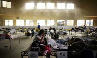 Tyra Abo sits on a cot at a makeshift evacuee center in Lac la Biche, Alberta on May 5, 2016, after fleeing forest fires north of Fort McMurray. Raging wildfires pressed in on the Canadian oil city of Fort McMurray Thursday after more than 80,000 people were forced to flee, abandoning fire-gutted neighborhoods in a chaotic evacuation. No casualties have been reported from the monster blaze, which swept across Alberta's oil sands region driven by strong winds and hot, dry weather.  /