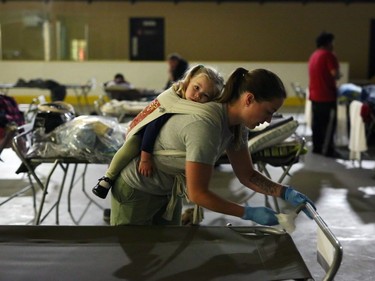 Marlee Hildebrandt and her daughter Oakley Hildebrandt, 2, clean cots at a makeshift evacuee center in Lac la Biche, Alberta on May 5, 2016, after fleeing forest fires north of Fort McMurray. Raging wildfires pressed in on the Canadian oil city of Fort McMurray Thursday after more than 80,000 people were forced to flee, abandoning fire-gutted neighborhoods in a chaotic evacuation. No casualties have been reported from the monster blaze, which swept across Alberta's oil sands region driven by strong winds and hot, dry weather.