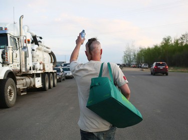 Les Wiley of Cold Lake, Alberta hands out bottles of water to people fleeing their homes threatened by forest fires in Wandering River on May 4, 2016.