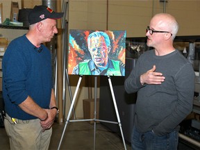 Fort McMurray Fire chief Darby Allen (L) and artist Russell Thomas chat as Allen is presented with an original painting from Thomas in Calgary, Alta on Tuesday May 17, 2016. Allen saw the popular painting in person for the first time as reproductions were being made at Run Digital. Profits from the sale will go to charity.