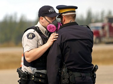 FORT MCMURRAY, ALBERTA: MAY 5, 2016 - Two police officers wear masks to protect themselves from falling ash in the air at a road block on Alberta Highway 63 near Fort McMurray on May 5, 2016. An out-of-control wildfire covering over 10,000 hectares of forest has forced the evacuation of Fort McMurray, the fourth largest city in Alberta. Over 80,000 residents of the northern Alberta city have been evacuated as fire threatens to consume the city and surrounding area. A provincial state of emergency has been declared in Alberta.