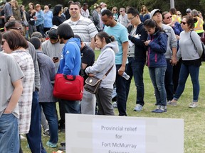 Fort McMurray evacuees line up at the Red and White Club in Calgary, Alta., on Wednesday May 11, 2016, to receive their cash cards from the province.