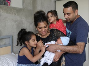 Fort McMurray evacuees Saira Younis and her husband Furkhan admire the newest member of their family, baby Rahim with their older children Inaya, 5, and Zuneira, 2, at the SAIT evacuation centre where they are staying in Calgary.