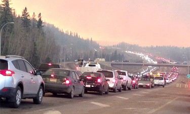Smoke fills the air as cars line up on a road in Fort McMurray, Alberta on Tuesday May 3, 2016 in this image provided by radio station CAOS91.1.