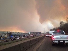 Smoke fills the air as cars line up on a road in Fort McMurray, Alberta on Tuesday May 3, 2016.