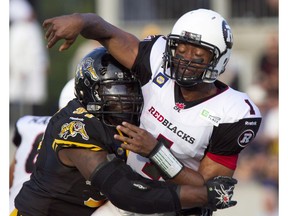 Ottawa RedBlacks quarterback Henry Burris, right, is hit by Hamilton Tiger-Cats tackle Ted Laurent as he makes a pass in first quarter CFL action in Hamilton, Ont., Saturday, July 26, 2014.