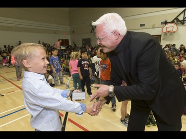 Britton Walker, 8, happily receives a stack of James Bond cards from collector Wayne Rooke at Royal Oak School in Calgary, Alta., on Monday, May 16, 2016. Walker, a huge James Bond fan who has appeared on Ellen and who through whom he met Bond actor Daniel Craig, was given a large portion of collector Wayne Rooke's extensive trove of James Bond memorabilia; his school paid forward the generosity by raising money for Fort McMurray fire victims. Lyle Aspinall/Postmedia Network