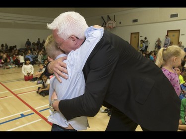 Britton Walker, 8, gets a hug from James Bond memorabilia collector Wayne Rooke at Royal Oak School in Calgary, Alta., on Monday, May 16, 2016. Walker, a huge James Bond fan who has  appeared on Ellen and who through whom he met Bond actor Daniel Craig, was given a large portion of collector Wayne Rooke's extensive trove of James Bond memorabilia; his school paid forward the generosity by raising money for Fort McMurray fire victims. Lyle Aspinall/Postmedia Network