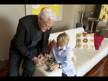 Britton Walker, 8, looks at James Bond trading cards with collector Wayne Rooke in Walker's home in Calgary, Alta., on Monday, May 16, 2016. Walker, a huge James Bond fan who has  appeared on Ellen and who through whom he met Bond actor Daniel Craig, was given a large portion of collector Wayne Rooke's extensive trove of James Bond memorabilia; his school paid forward the generosity by raising money for Fort McMurray fire victims. Lyle Aspinall/Postmedia Network