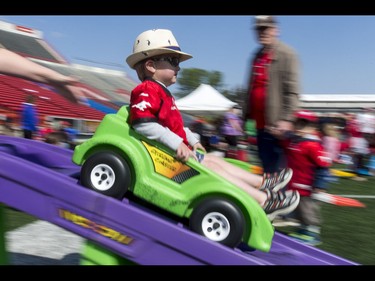 Jax Pugh, age 2, zips down a small track during the Calgary Stampeders Fanfest at McMahon Stadium in Calgary, Alta., on Saturday, May 14, 2016. The event featured player autographs, a pancake breakfasts and family games. Lyle Aspinall/Postmedia Network