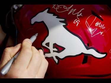 An autograph is signed on a helmet during the Calgary Stampeders Fanfest at McMahon Stadium in Calgary, Alta., on Saturday, May 14, 2016. The event featured player autographs, a pancake breakfasts and family games. Lyle Aspinall/Postmedia Network