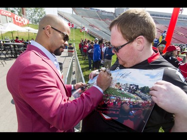 Recently retired star Jon Cornish signs a photo for fan Kent Johnson during the Calgary Stampeders Fanfest at McMahon Stadium in Calgary, Alta., on Saturday, May 14, 2016. The event featured player autographs, a pancake breakfasts and family games. Lyle Aspinall/Postmedia Network