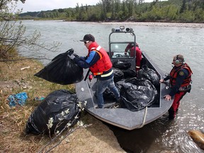 Contractor Jordan Brisbourne unloads bags of garbage collected on the unnamed island in the Bow River off the Montgomery shore into a Calgary Fire Department boat Wednesday afternoon. Bylaw Services and the contractors cleaned up the island, nicknamed Heroin Island because of drug paraphernalia found there last month.