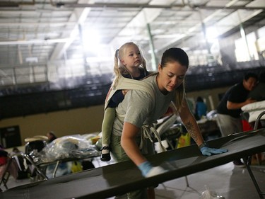 Marlee Hildebrandt and her daughter Oakley Hildebrandt, 2, clean cots at a makeshift evacuee center in Lac la Biche, Alberta on May 5, 2016, after fleeing forest fires north of Fort McMurray. Raging wildfires pressed in on the Canadian oil city of Fort McMurray Thursday after more than 80,000 people were forced to flee, abandoning fire-gutted neighborhoods in a chaotic evacuation.