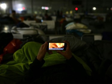 A man uses his mobile phone as he lays on a cot at a makeshift evacuee centre in Lac la Biche, Alberta on May 5, 2016, after fleeing forest fires north of Fort McMurray.