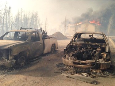 Local Input~ A car and truck are burned out in front of a house on fire in Fort McMurray, Alberta  MUST CREDIT: Loren Andreae/Global TV News