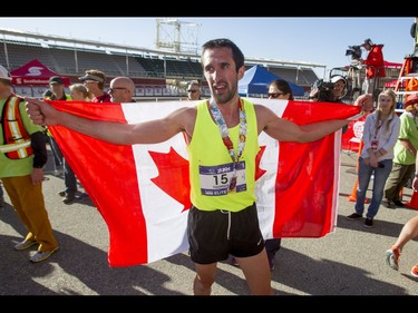 Thomas Toth carries the Canadian flag after winning the men's half-marathon during the Calgary Marathon at the Stampede Grounds in Calgary, Alta., on Sunday, May 29, 2016. There were 5k, 10k, 21.1k, 42.2k and 50k distances in the race, including the half-marathon national championships. Lyle Aspinall/Postmedia Network